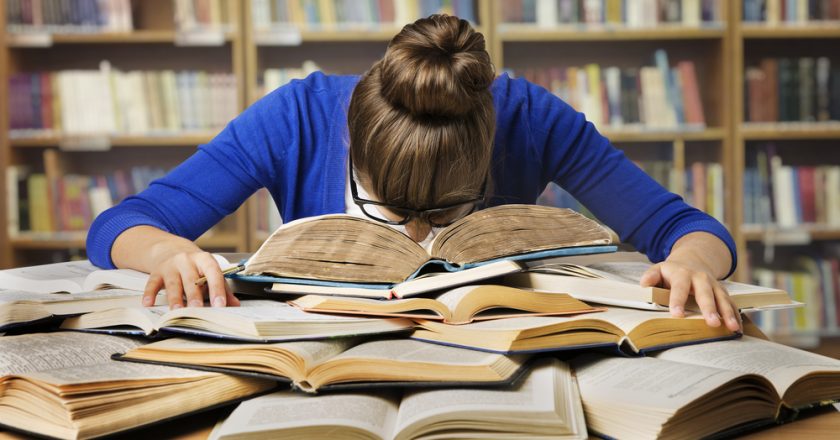 Girl studies for post-graduate degree with head in her books